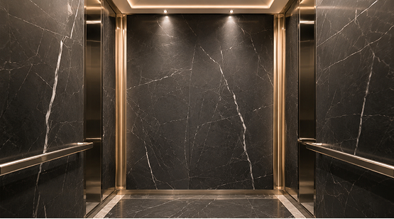 Elevator interior lined with black marble panels featuring thin white veining and warm LED downlighting
