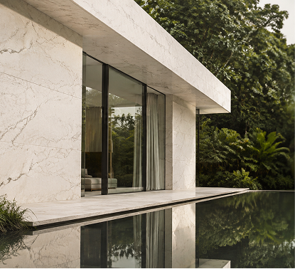 Modern residential exterior featuring white marble wall cladding alongside a luxury swimming pool with lush tropical landscaping